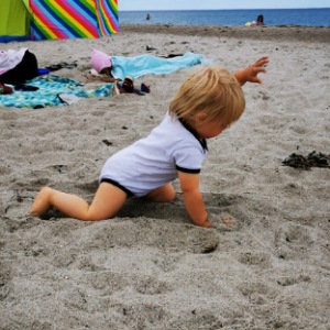 Kleinkind krabbelt durch den Sand am Strand