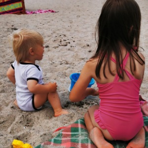 Zwei Kinder spielen mit Eimer und Förmchen am Strand